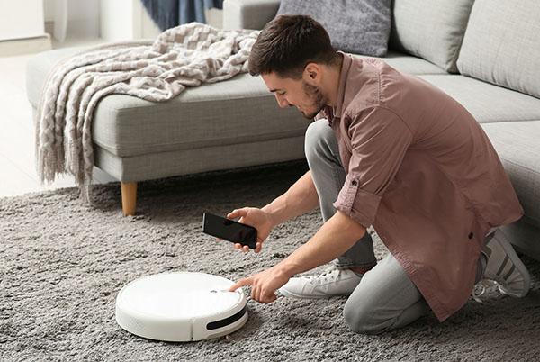 a man is using a robot vacuum to clean the floor