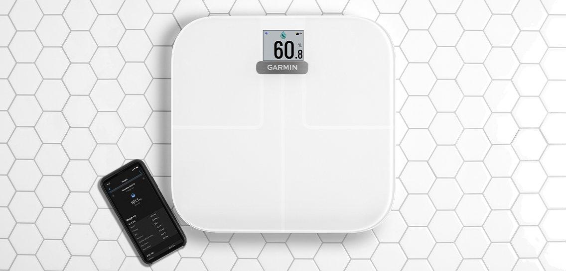 a white Garmin scale with a phone on a tiled floor