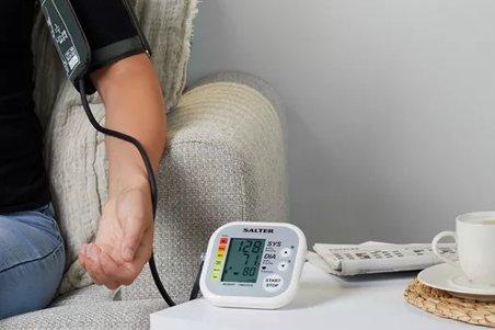 a person sitting on a couch with a blood pressure monitor