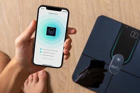 a person holding an smart phone next to a smart scale