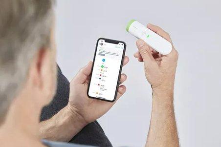 a man holding a mobile phone and a digital thermometer