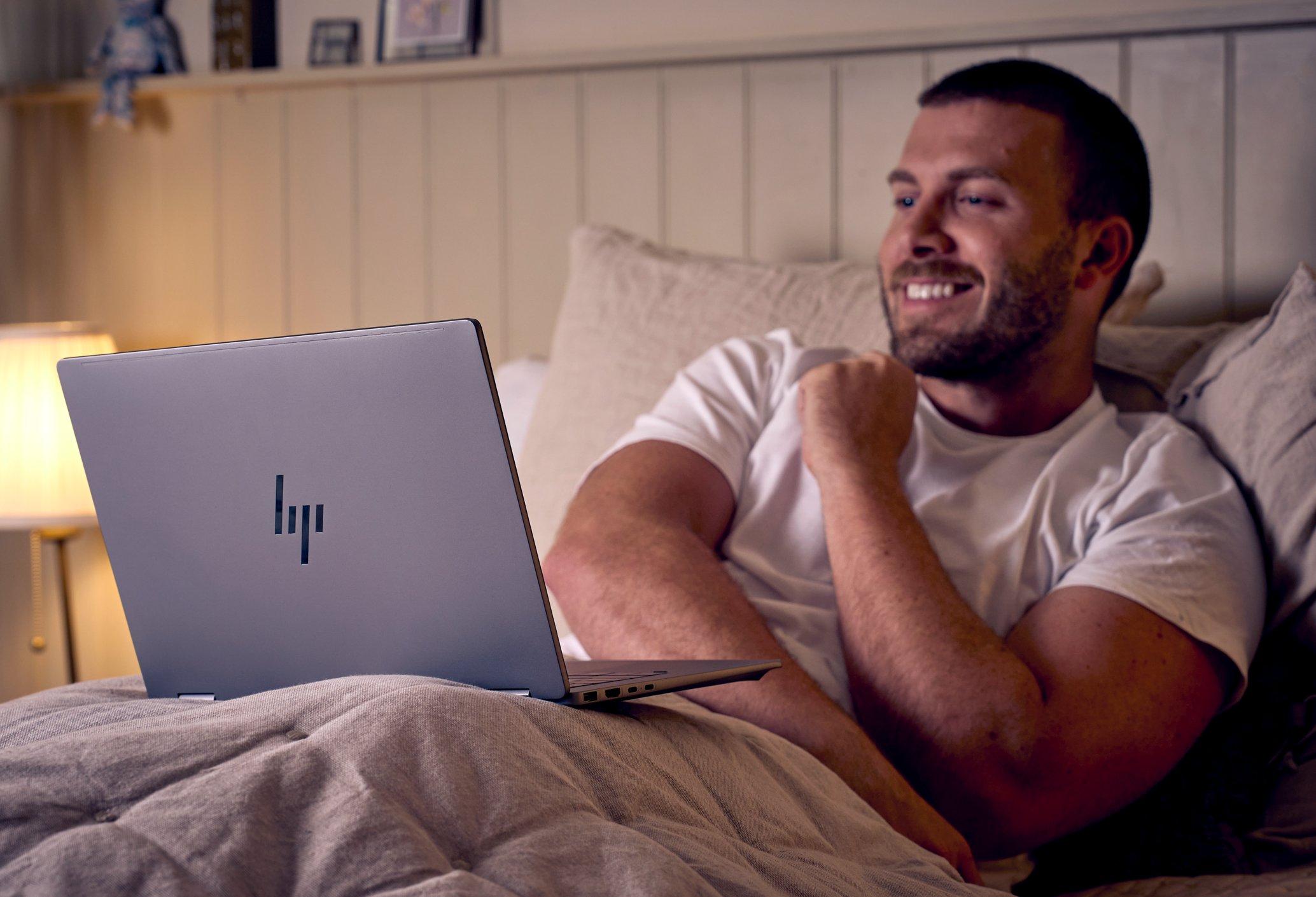 a man laying in bed with laptop on his chest