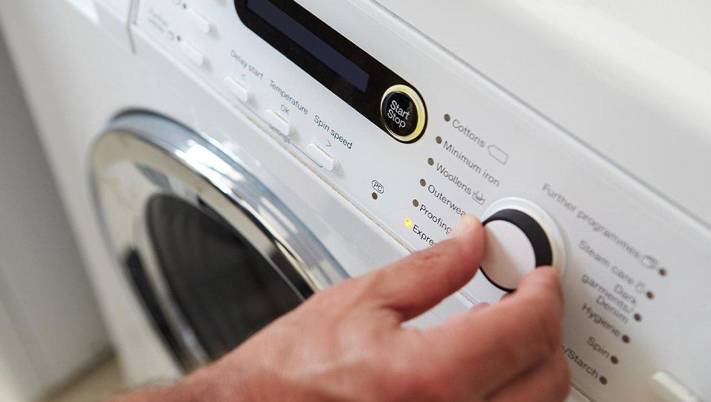 person changing settings on a washing machine