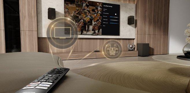 A remote control on a sofa pointing to a TV with icons on top showing what the buttons do