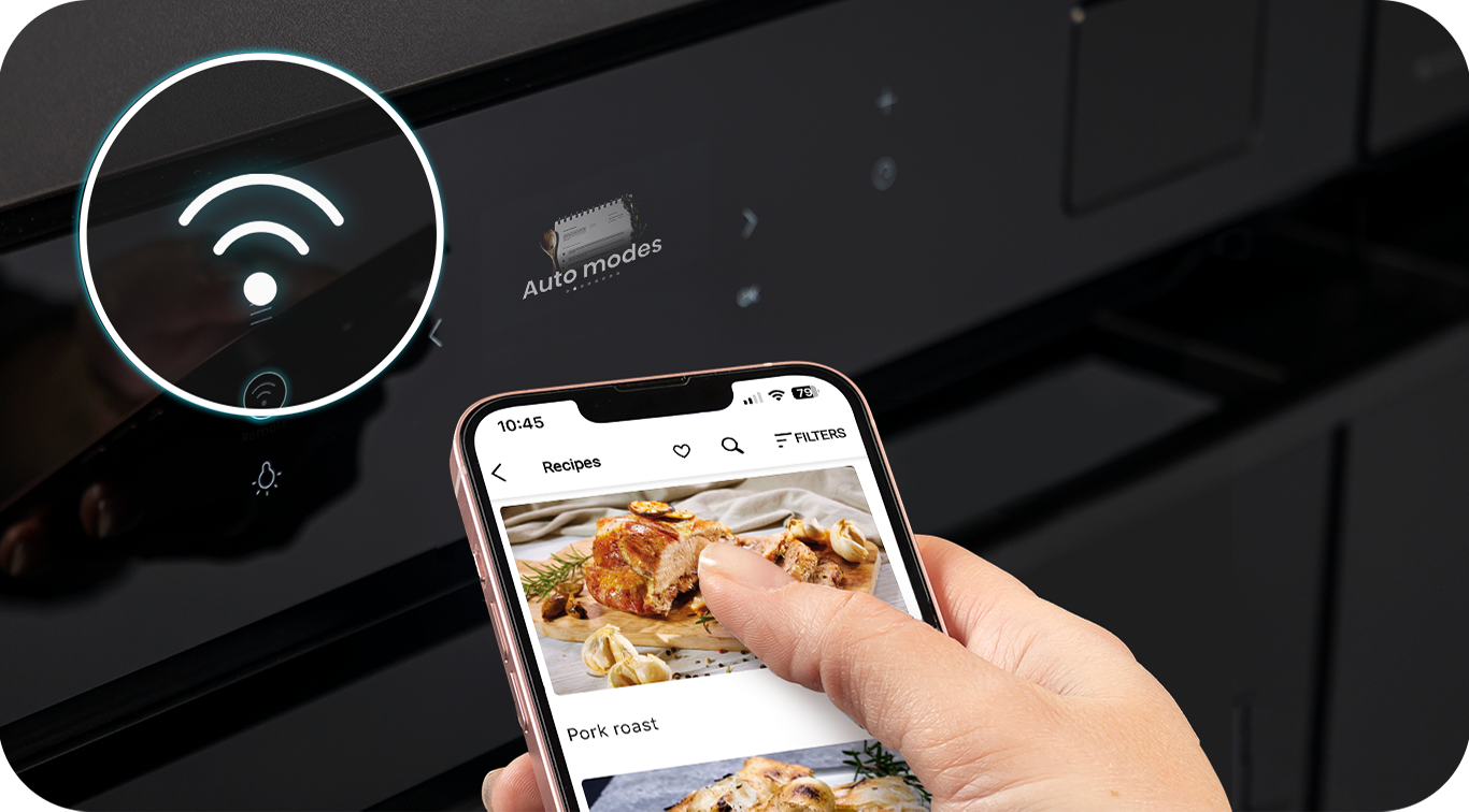 A hand using a mobile phone in front of an oven