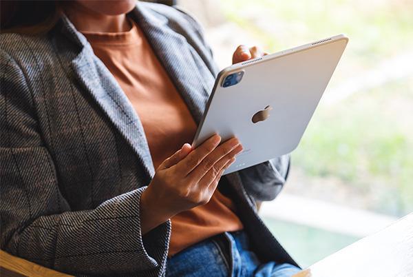 a woman sitting at a table with an ipad pro in her hand