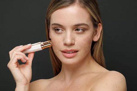 a woman with a cell phone in her hand and a brush on her face