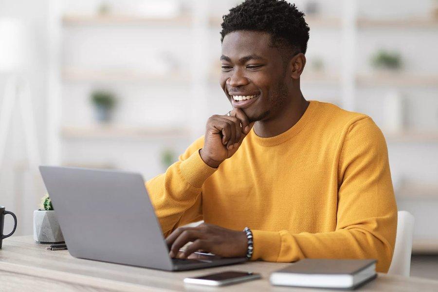A man smiling whilst using a laptop