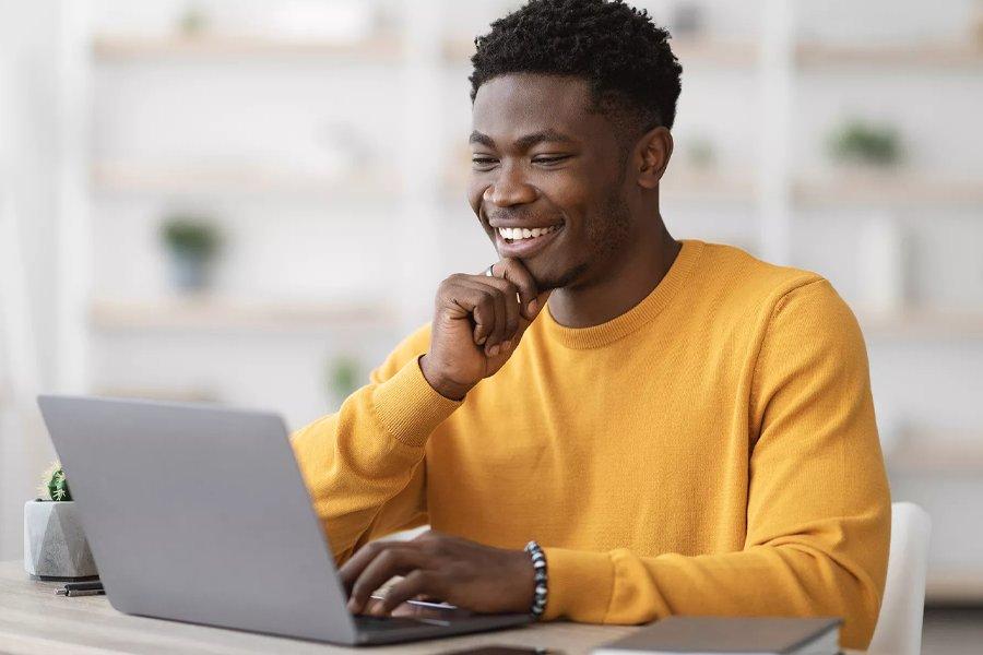 A man smiling whilst looking at a laptop