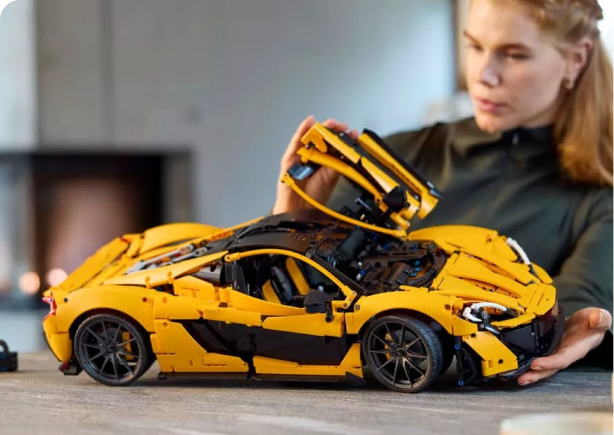 A woman building a yellow and black LEGO sports car