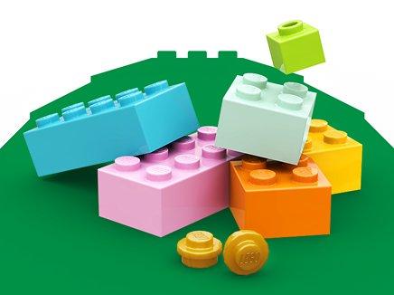 Six LEGO blocks and two LEGO coins on a green background