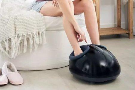 a woman sitting on a chair with a foot massager on her foot