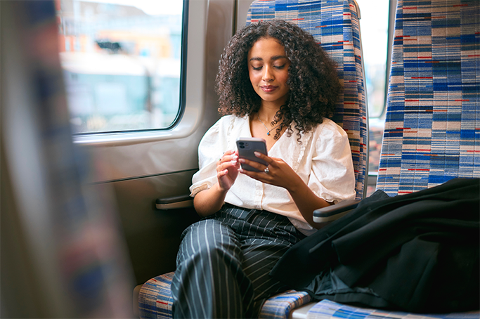 A woman sitting on a train looking at her phone