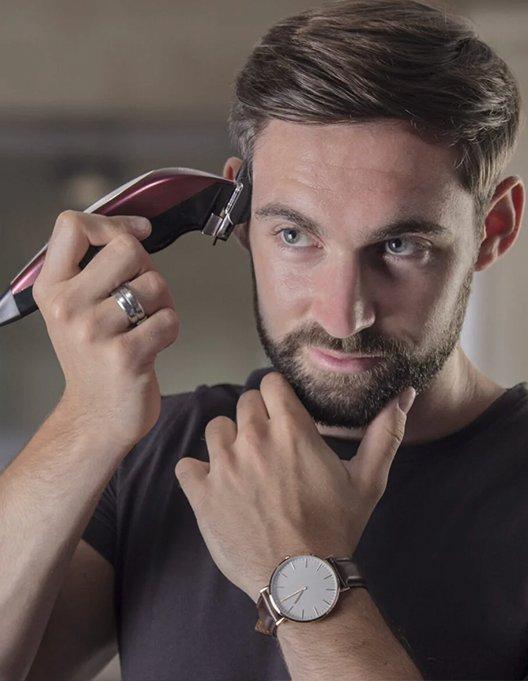 a man with a beard and a watch is getting his hair cut