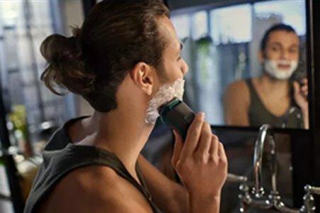 a man shaving his face in front of a mirror