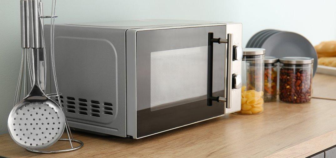 A microwave on a counter next to utensils and jars