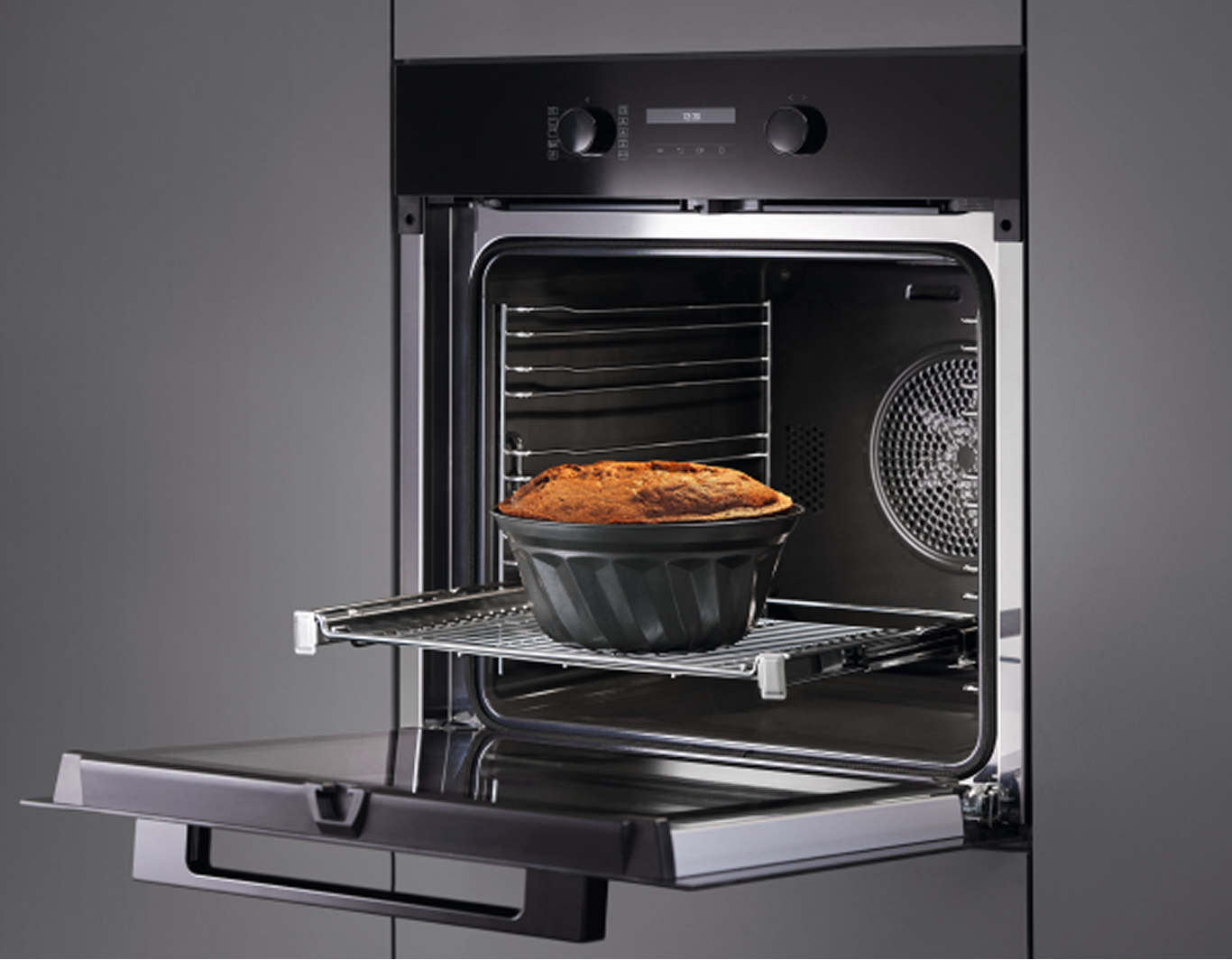An open built-in oven with food on a shelf