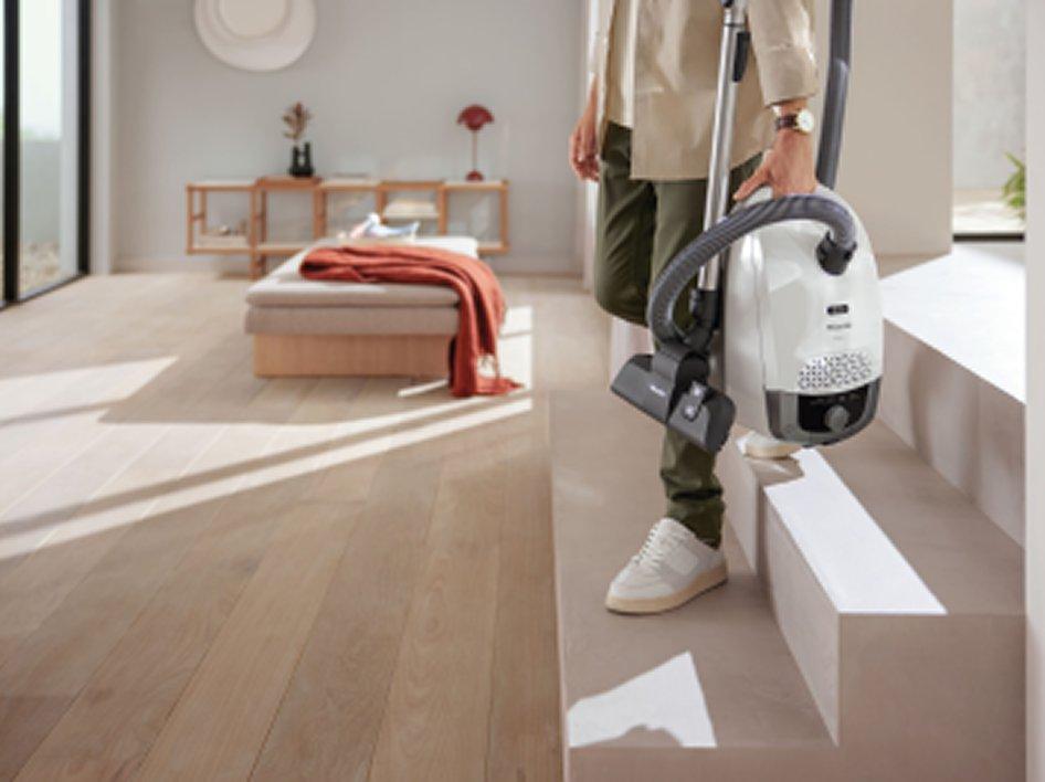 A person carrying a vacuum cleaner down a set of stairs