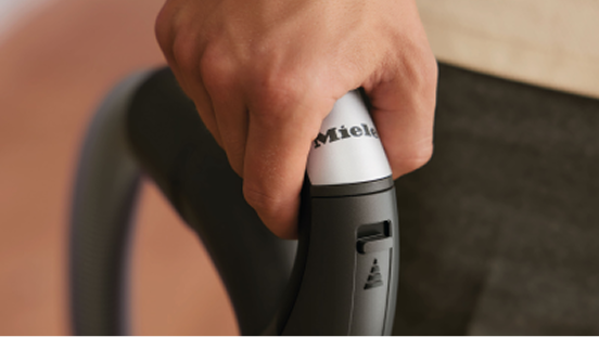 Close up of a hand holding a vacuum cleaner handle