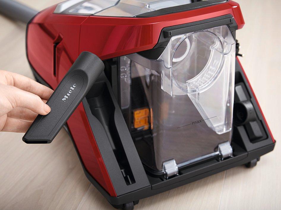 A hand holding a vacuum cleaner attachment next to a vacuum cleaner