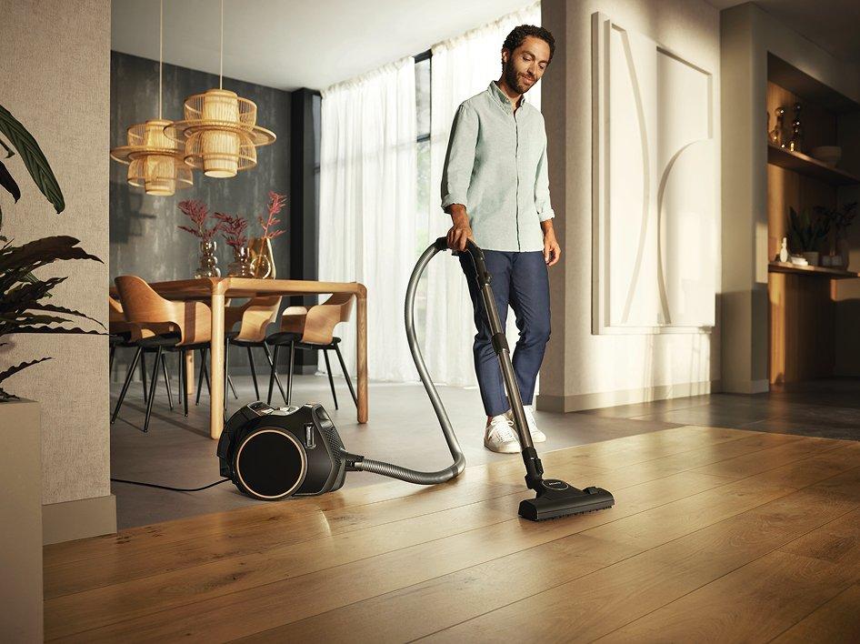 A man using a vacuum cleaner on a wooden floor