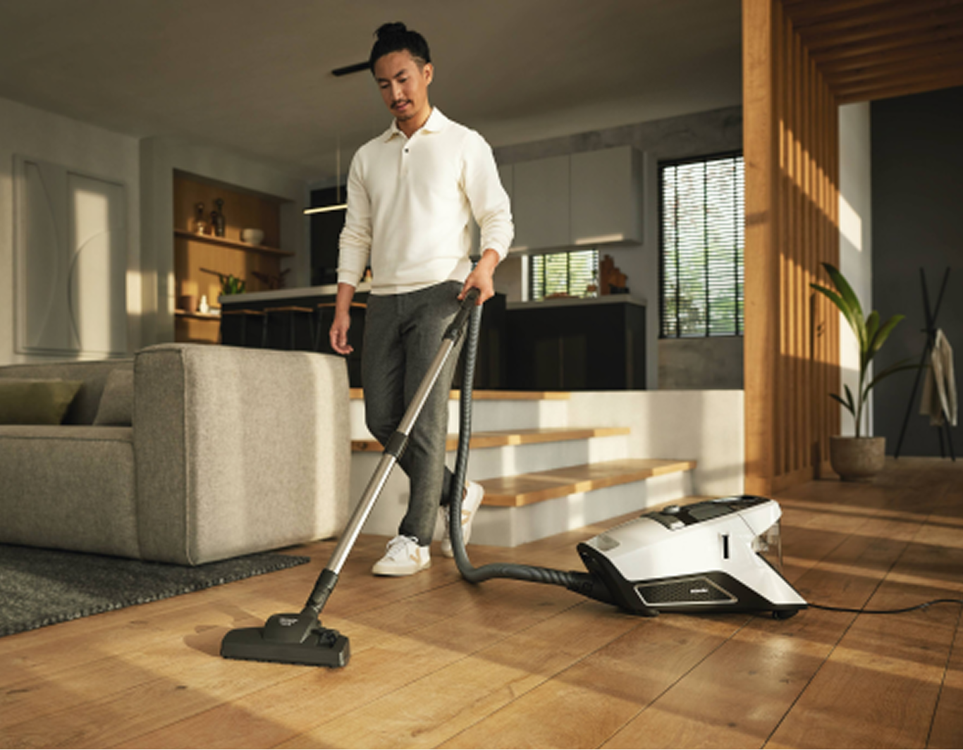 A man using a corded bagless vacuum cleaner on a hardwood floor