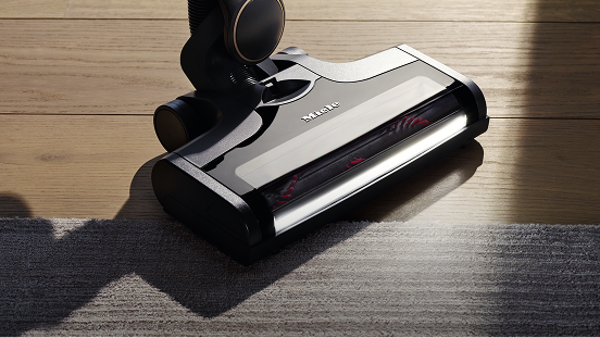 A vacuum cleaner head on a laminate and carpeted floor