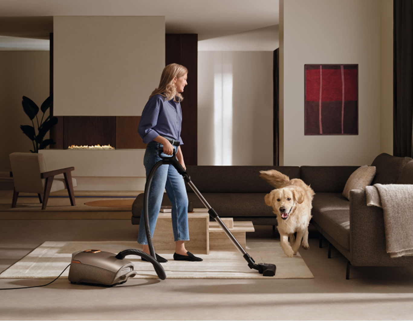 A woman hoovering a living room next to a dog