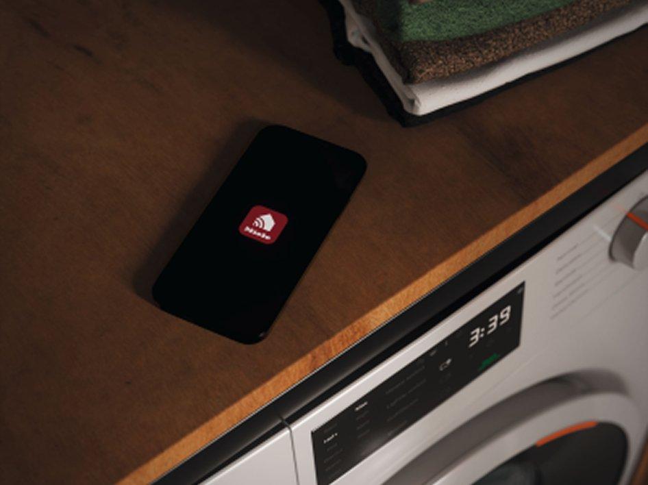 A smart phone is lying on a counter above a washing machine