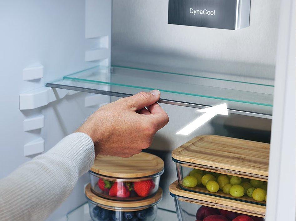 Inside a fridge with a hand pushing a shelf in