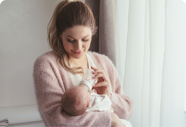 A new mum holds her baby whilst feeding it with a bottle