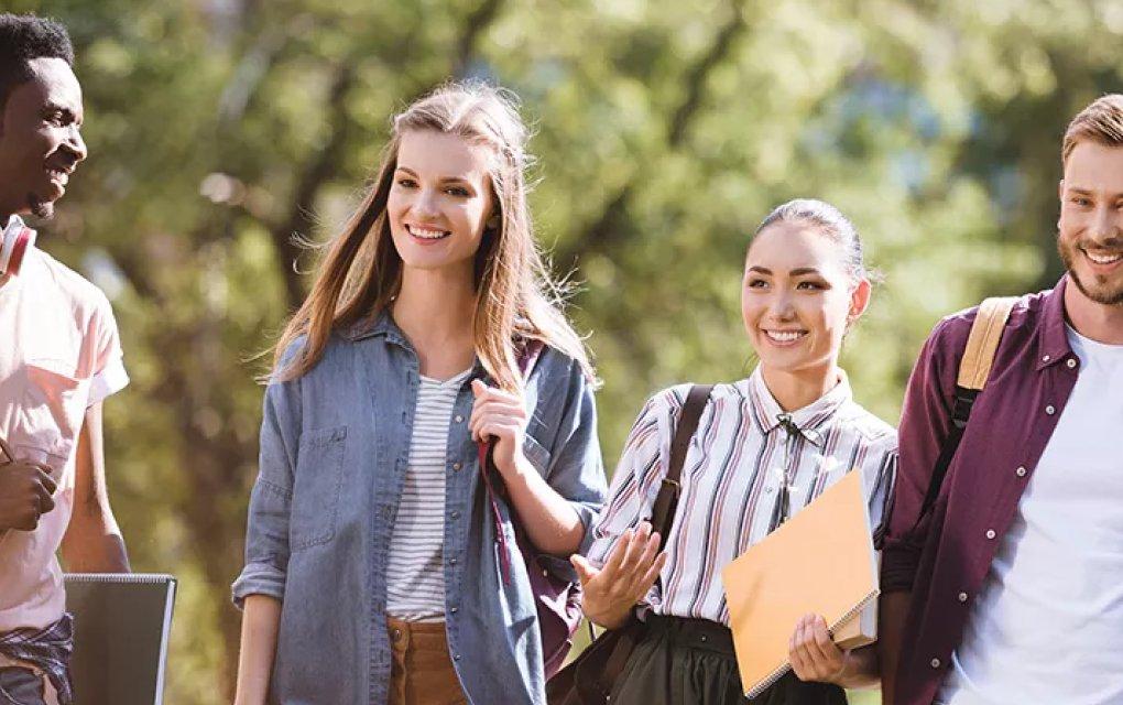 Four students walking in an area with trees