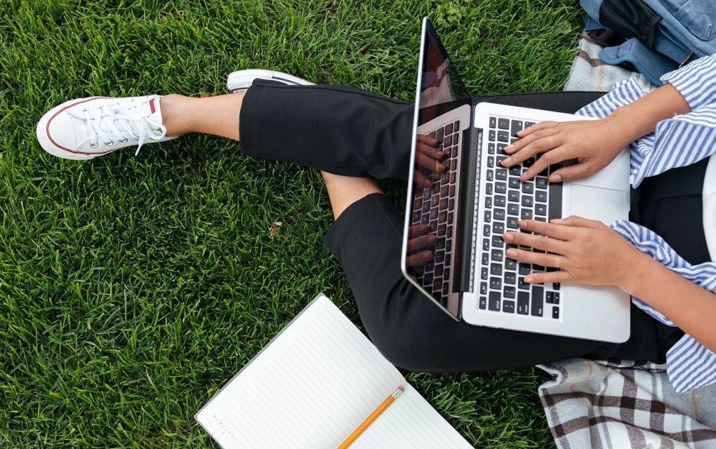 A person sitting on grass using a laptop