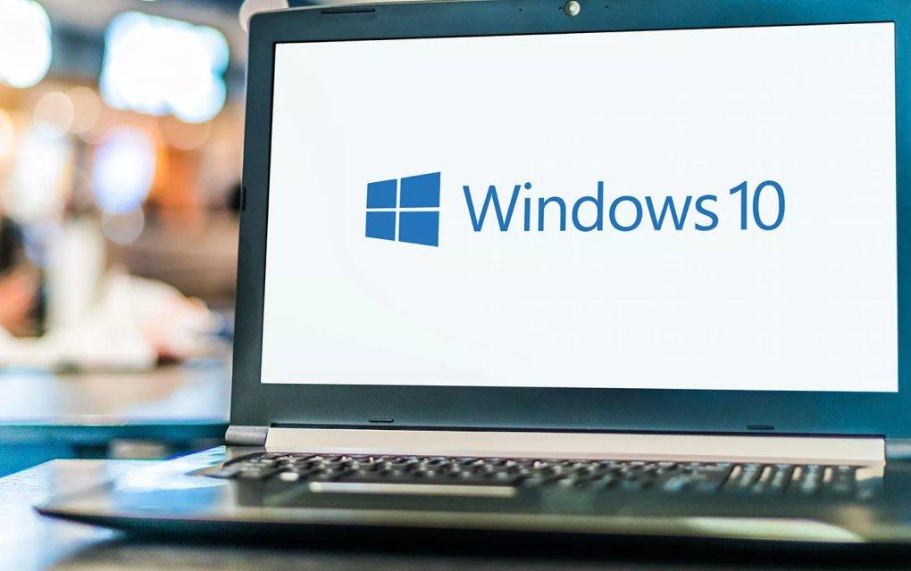 A man sitting at a table looking at a laptop