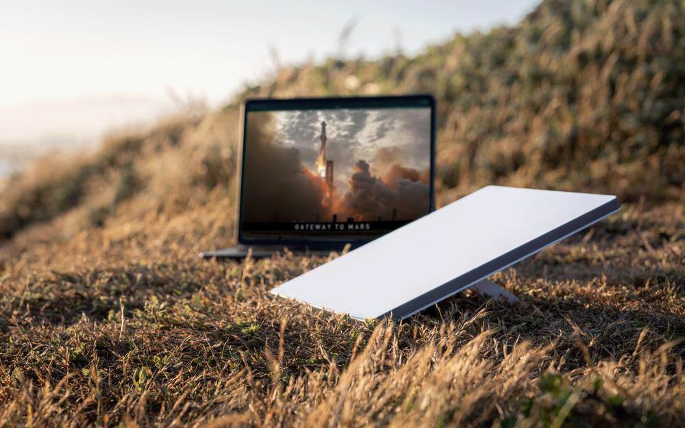 A Starlink dish and laptop on a remote hill