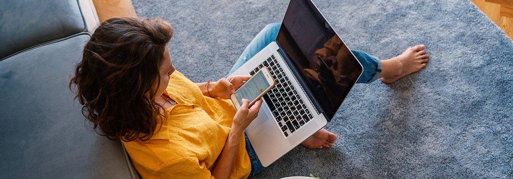 a woman sitting on a couch with a laptop and a cell phone