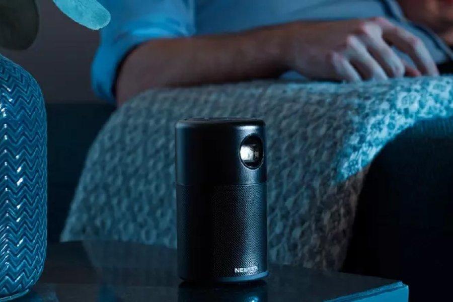 A small black projector next to the arm of a sofa