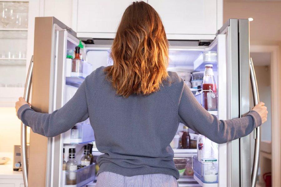 A woman holding open a fridge