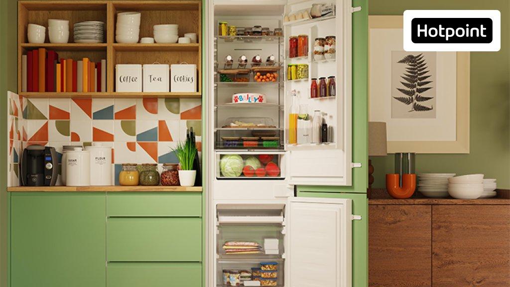 A kitchen with green cabinets and a built-in Hotpoint fridge freezer