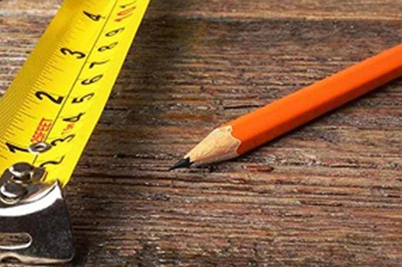 A tape measure and a pencil on a wooden surface