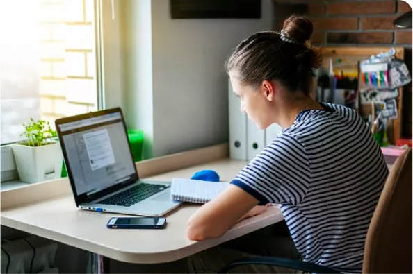 a woman sitting at a desk with a laptop and a phone