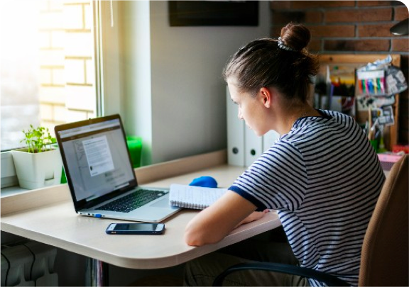 a woman sitting at a desk with a laptop and a phone