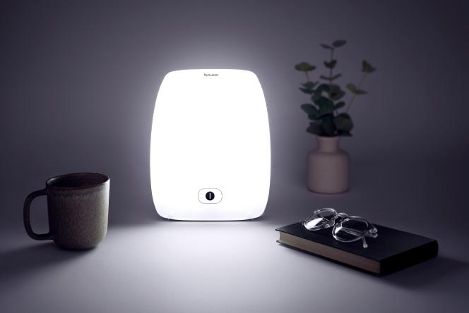 A bright lamp on a desk with a book and a mug