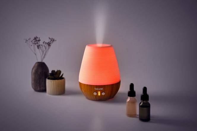 A diffuser with light, next to oils and a plant
