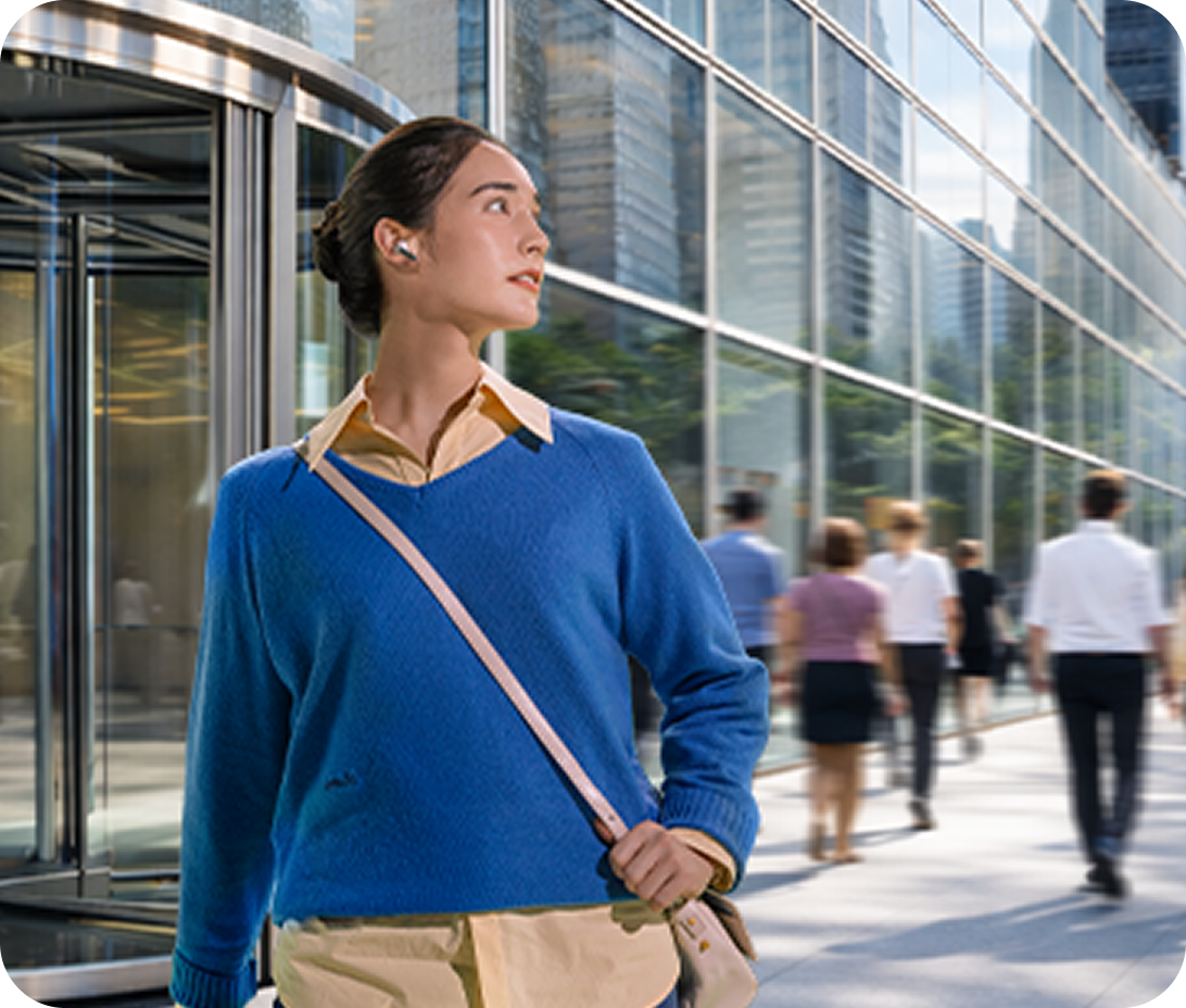 A woman standing in front of an office building wearing earbuds