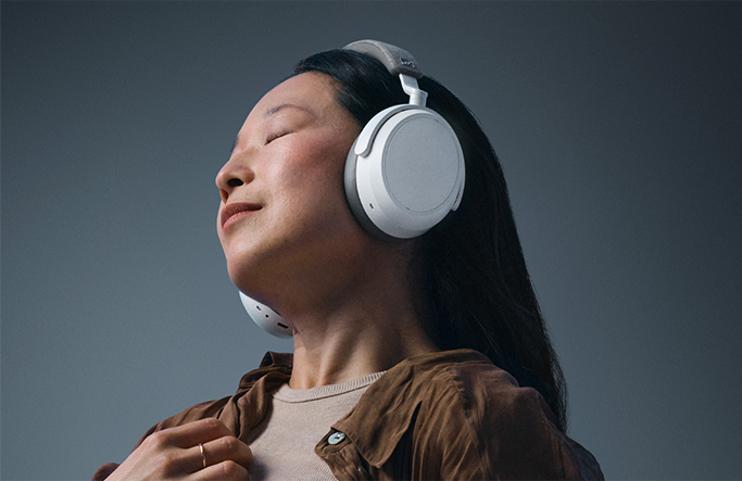 A woman with her eyes closed wearing a pair of white over-ear headphones