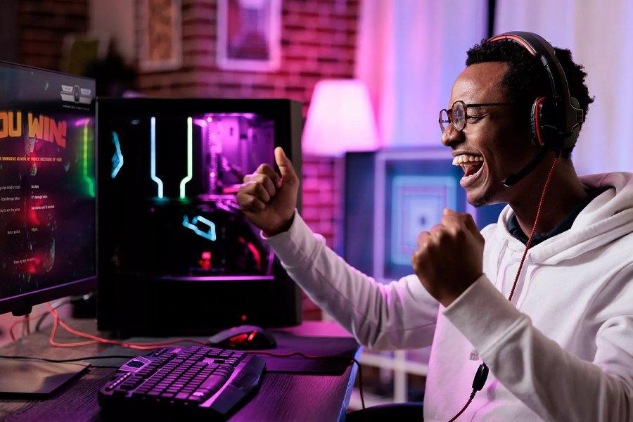 A man cheering at a PC screen that says you win on it