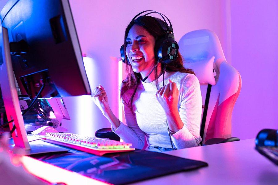 A woman cheering whilst sitting at a desk and looking at a monitor
