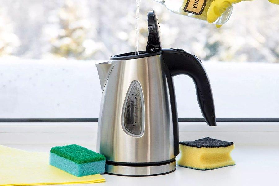 Someone pouring liquid from a bottle into an open kettle surrounded by cloths and sponges