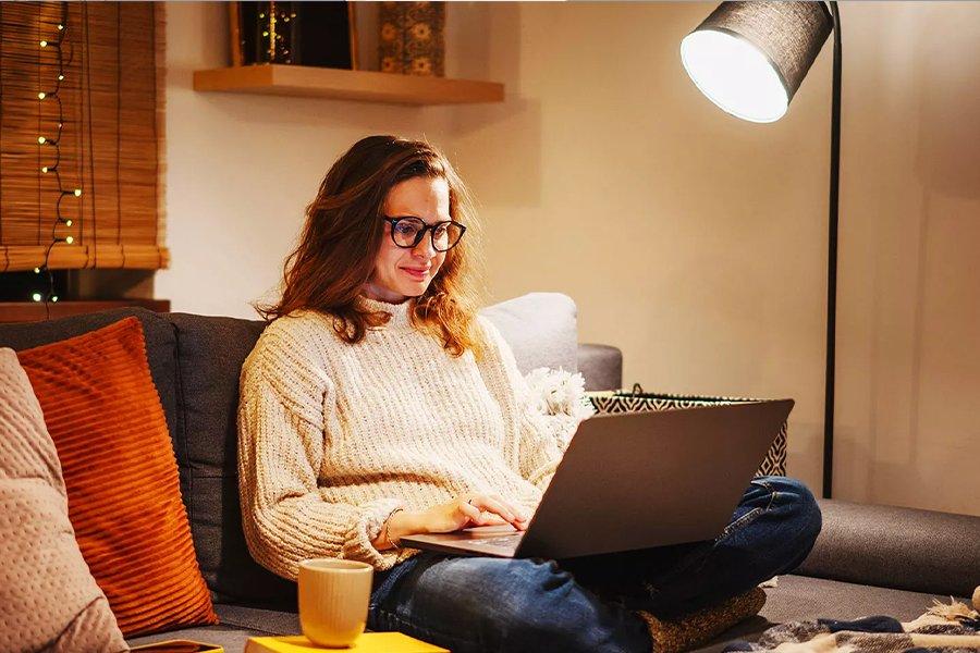 A woman sitting on a sofa using a laptop